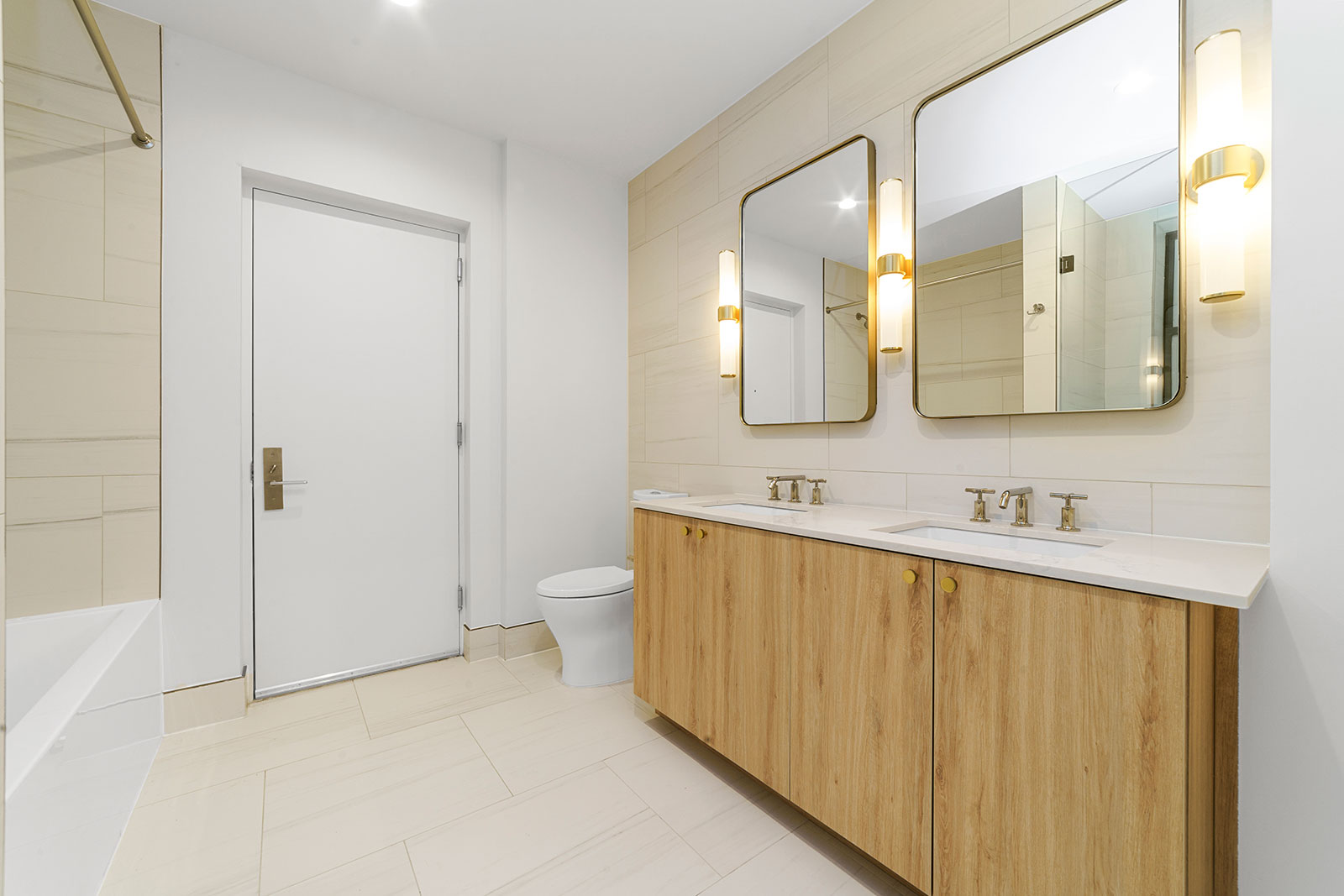 Pet-Friendly Apartments in Upper West Side Manhattan, NY - 125 Riverside - Bathroom with Tile Floors and Walls, Light Wood-Style Cabinets, 2 Mirrors, a White Bathtub and Toilet, and Stylish Decor